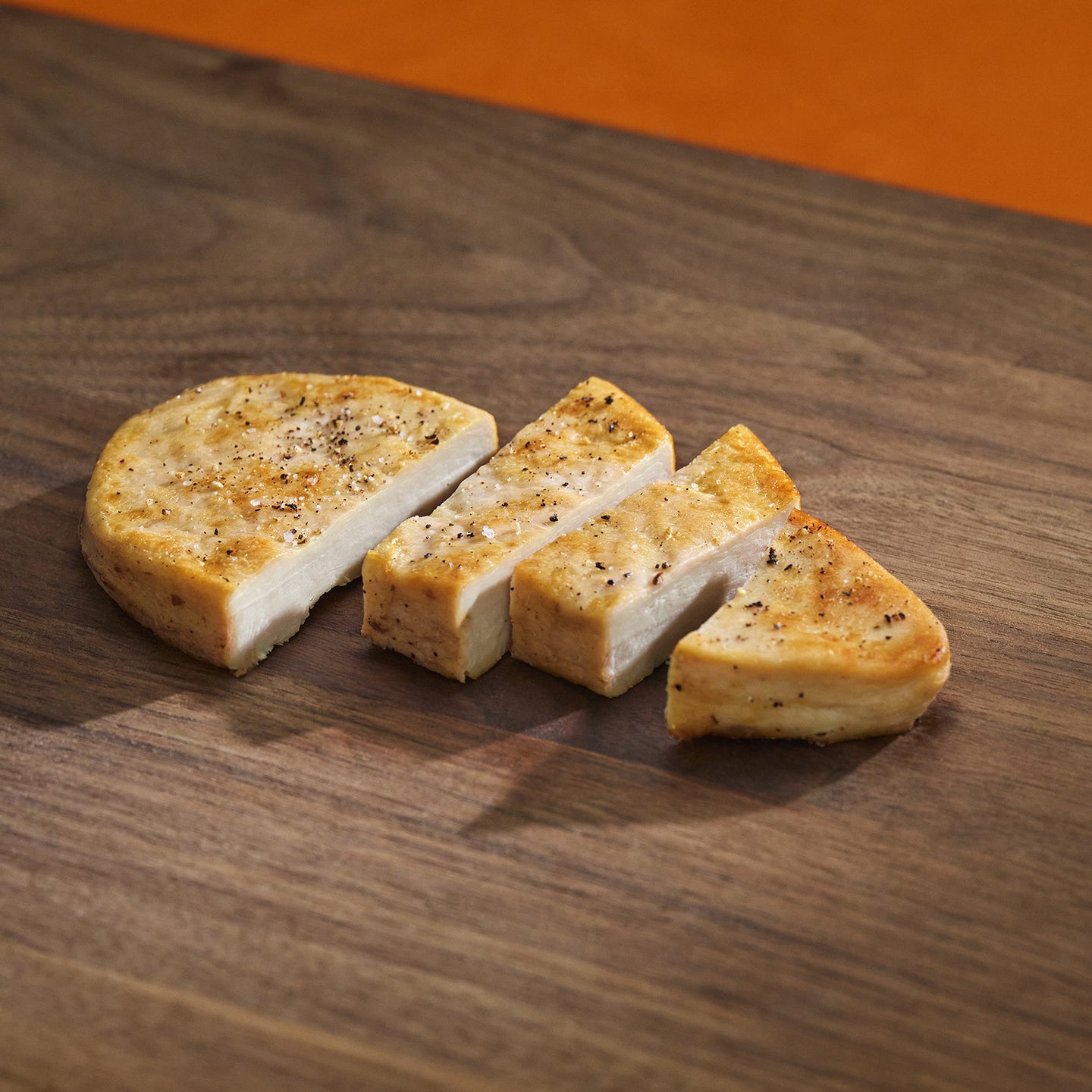 Sliced bread on a wooden surface with an orange background